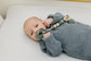 Newborn in gray knit outfit using Mila & Lulu sage round silicone pacifier with beaded wood clip